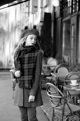 Fototapeta na wymiar young girl in a red beret and a gray coat near a cafe
