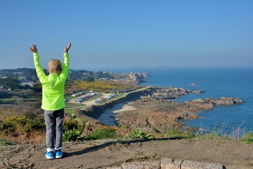 Petit garçon qui regarde la mer sur la côte de granit rose en Bretagne. France