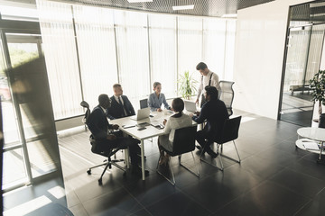 Silhouettes of people sitting at the table. A team of young businessmen working and communicating together in an office. Corporate businessteam and manager in a meeting