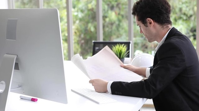 Architect man checking Blueprint with computer on desk in the workplace. engineer  in office . business construction project