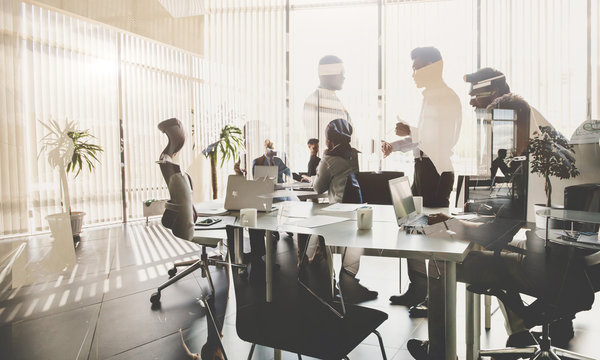 Silhouettes Of People Against The Window. A Team Of Young Businessman Working And Communicating Together In An Office. Corporate Business Team And Manager In A Meeting.