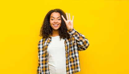 young pretty african american woman smiling and looking friendly, showing number four or fourth...