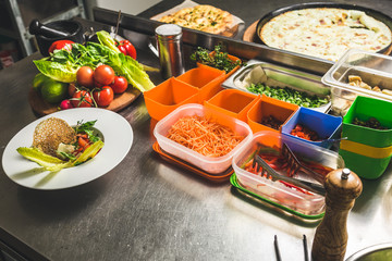 Professional chef cooking in the kitchen restaurant at the hotel, preparing dinner. A cook in an apron makes a salad of vegetables and pizza.