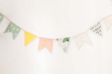 wall is decorated with multi-colored flags for children. Birthday decor decoration flags. Decor for the holiday. party flags hanging on white background, decorate items for festival, celebrate event