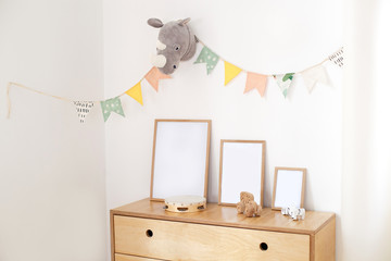 concept of a cozy interior, housewarming. Photo frames on a wooden chest of drawers near a white...