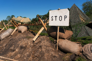 A moat with water and wooden fences in a circle of military campgrounds.