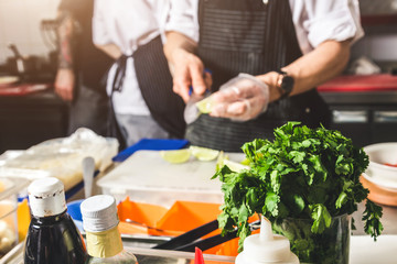 Professional chef cooking in the kitchen restaurant at the hotel, preparing dinner. A cook in an apron makes a salad of vegetables and pizza.