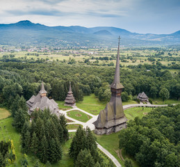 Aerial panoramic view of traditional ancient Maramures wooden orthodox church in Transylvania with highest wooden belltower in Europe, Romania. UNESCO world heritage site.