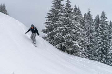 Snowboarder rides from powder snow hill. Mountain freeride snowboarding. Winter Carpathians