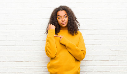 young black woman looking impatient and angry, pointing at watch, asking for punctuality, wants to...