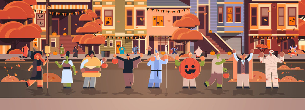 people wearing different monsters costumes walking in town tricks and treat happy halloween party celebration concept city street buildings cityscape background full length horizontal