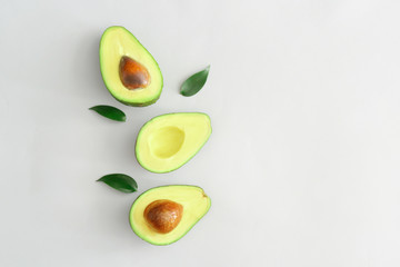 Halves of ripe avocado on white background