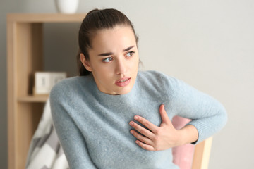 Young woman suffering from heart attack at home