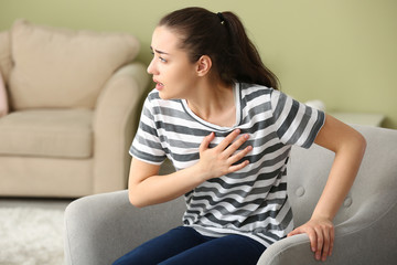 Obraz premium Young woman suffering from heart attack at home