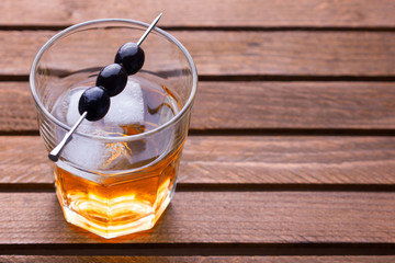 Glass of alcohol drink with olives on pick