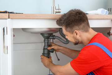 Plumber installing sink in kitchen