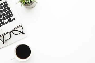 White office desk table with laptop computer, cup of coffee and supplies. Top view with copy space, flat lay.