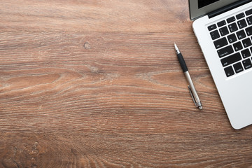 Wood office desk table with laptop computer and pen. Top view with copy space, flat lay.