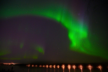 Northern polar light Aurora borealis multicolour light glowing under the starry dark  sky and water reflection from lake
