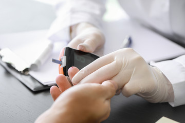 Doctor checking blood sugar level of diabetic patient in clinic, closeup