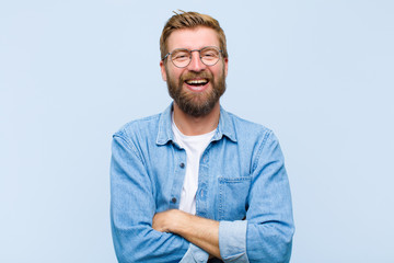 young blonde adult man looking like a happy, proud and satisfied achiever smiling with arms crossed