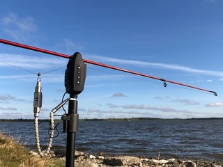 Spinning with a reel against the blue sky. Fishing rod and fishing tackle on the lake. Concept: male hobby, sport fishing.