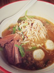 Delicious noodles with pork and pork balls with soup in white in Thai style food. Thai peoples call Boat Noodles, breakfast with bowl on wooden background meat. Noodle of traditional Thai food.