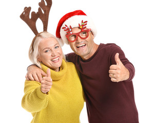 Portrait of happy mature couple with Christmas decor showing thumb-up gesture on white background