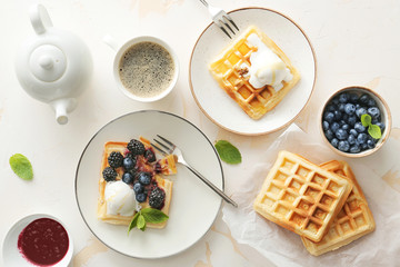 Tasty waffles with berries, ice-cream and coffee on white table