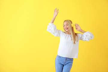 Beautiful young woman listening to music on color background