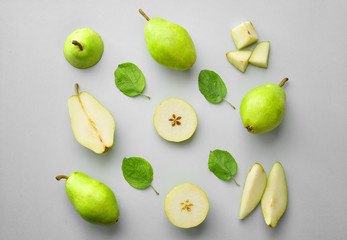 Tasty fresh pears with leaves on grey background