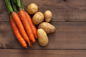 Fresh carrots and potatoes on a wooden background. Harvest season