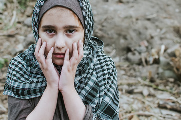 a refugee child in the war, a Muslim girl with a dirty face on the ruins, the concept of peace and...