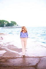 Smiling beautiful woman walking on the beach promenade in a small town