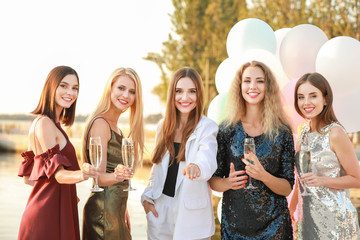 Beautiful young women drinking champagne at hen party outdoors