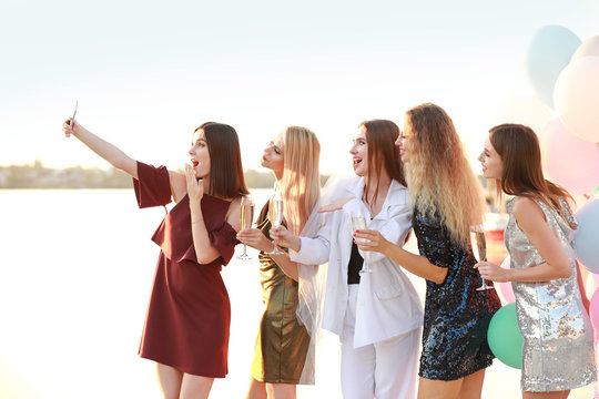 Beautiful young women taking selfie at hen party near river