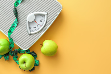 Scales, apples and measuring tape on color background. Weight loss concept