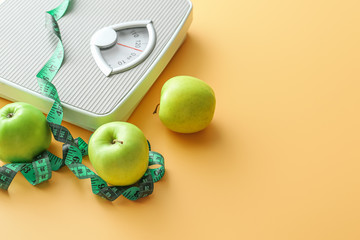 Scales, apples and measuring tape on color background. Weight loss concept