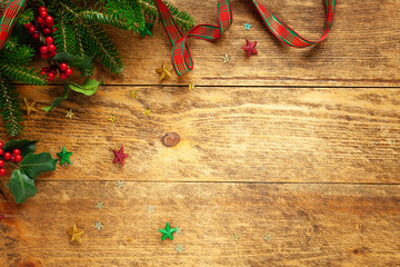 Christmas background with Christmas decor, branches of holly and fir on wooden background. Winter festive concept. Flat lay, copy space.