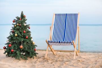 Sun lounger and Christmas tree on sea beach
