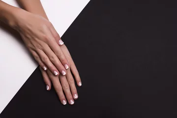 Rolgordijnen Beautiful hands with french manicure on black background © shumytskaya