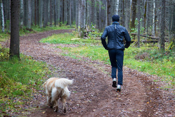 Naklejka na ściany i meble A man runs with a dog on the street. A man on the street doing sports.