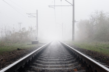 Railway track on misty foggy morning day in autumn