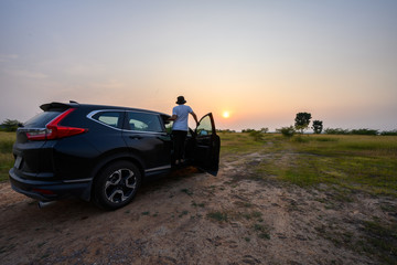 Travel concept, Female tourist standing watching sunset on the car