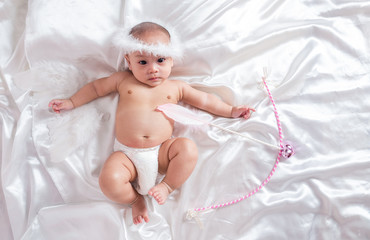 cute asian four-month baby in cupid dress smiling