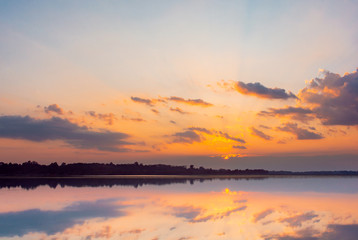 Obraz na płótnie Canvas Sunset reflection lagoon. beautiful sunset behind the clouds and blue sky above the over lagoon landscape background. dramatic sky with cloud at sunset.