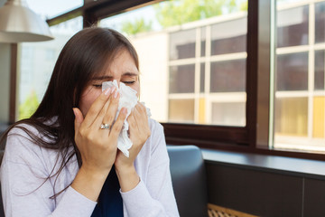 Brunette woman blowing nose into tissue
