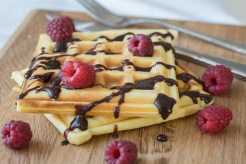 Two Viennese waffles with chocolate and berries on a wooden Board