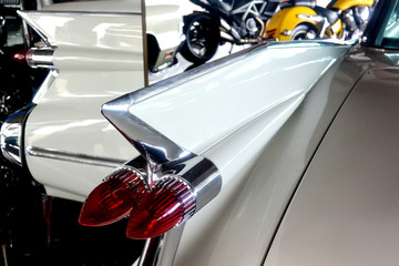 The rear wing of a white 1959 retro car, reflected in the mirrors, close-up