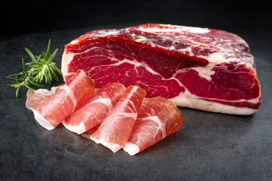 Traditioneller luftgetrockneter Parma Schinken angeboten auf schwarzen Hintergrund 